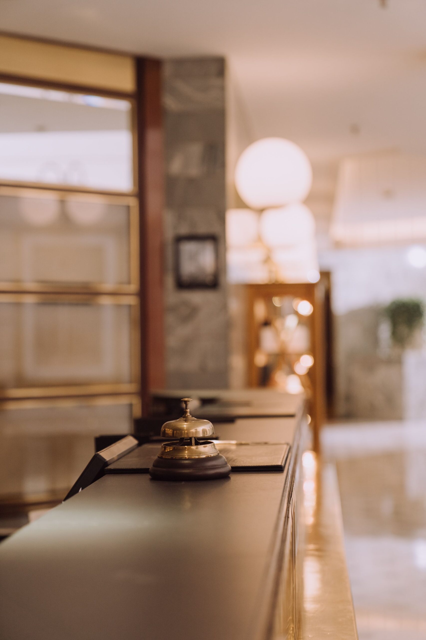 Close-up of a hotel reception desk with a classic bell and warm lighting