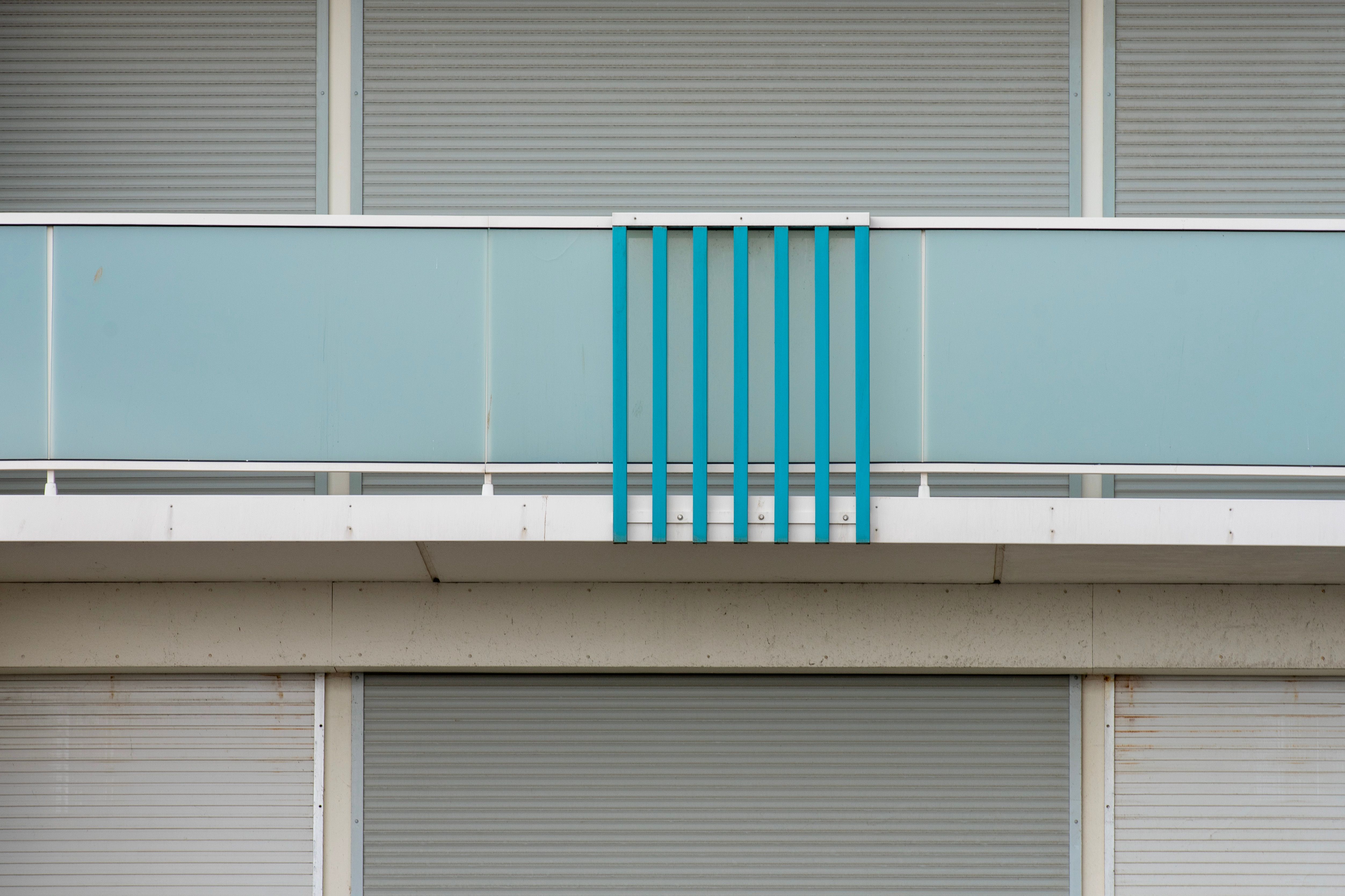 Contemporary balcony with glass panels and blue accents, representing lightweight modern exterior construction.