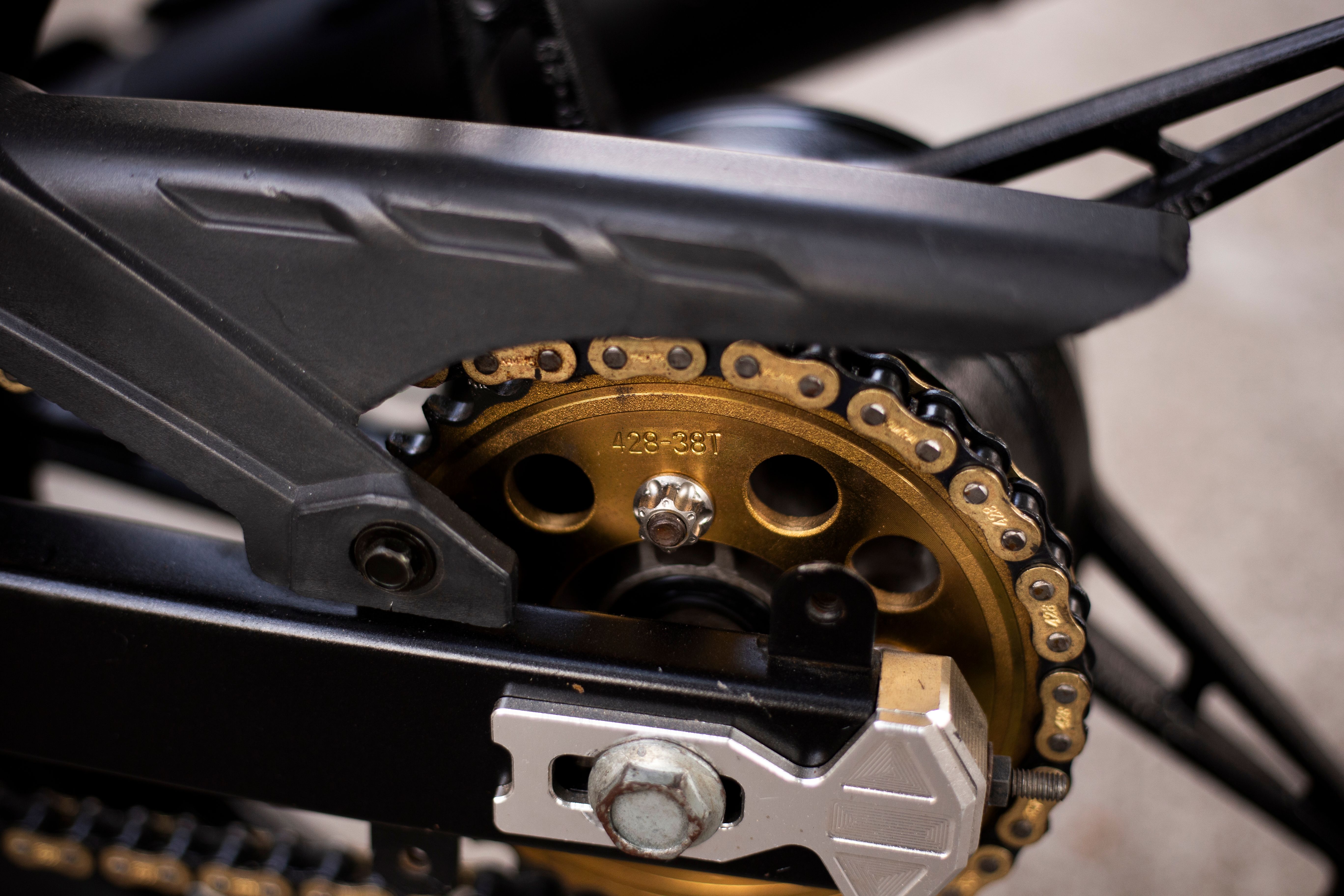 Close-up detail of a motorcycle chain and sprocket for a pre-trip drivetrain inspection.