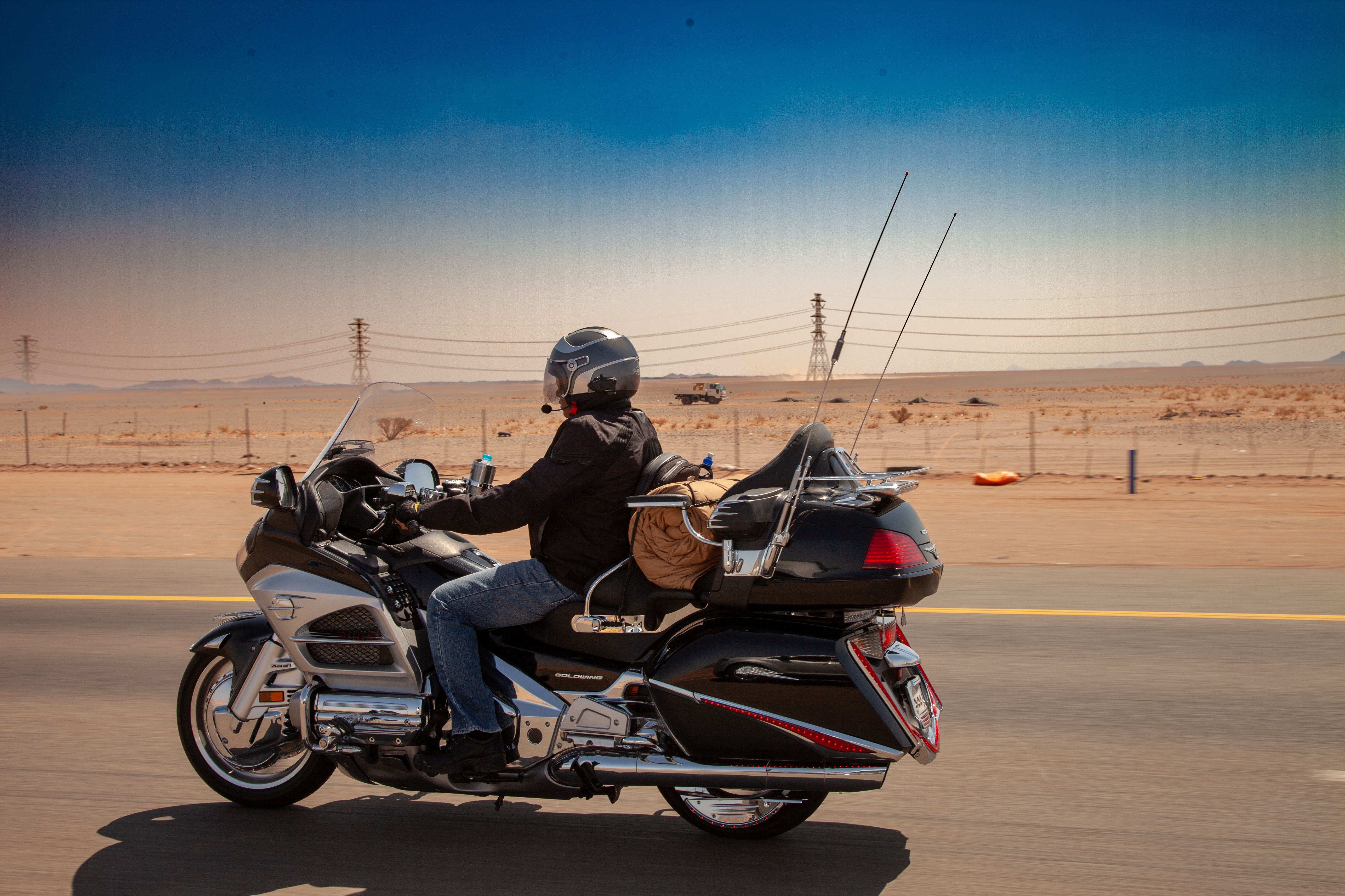 Motorcyclist traveling along a highway through a wide-open desert landscape.